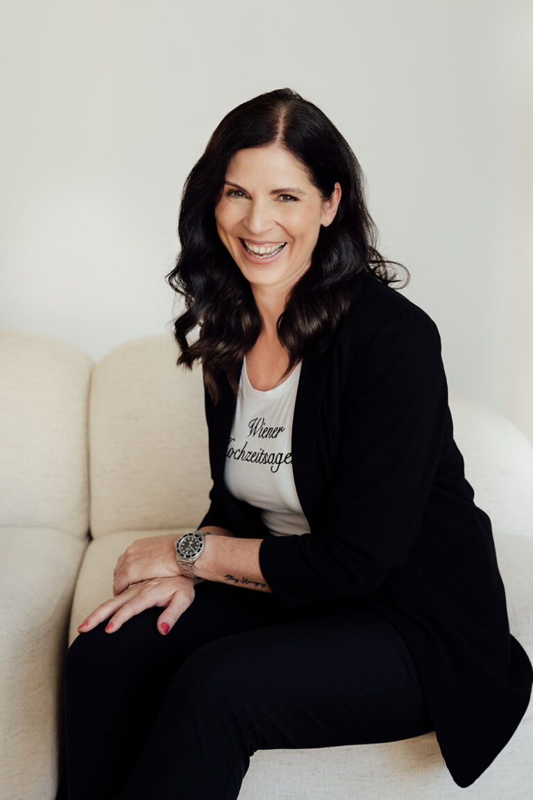 Uschi sitzt auf Couch und lächelt